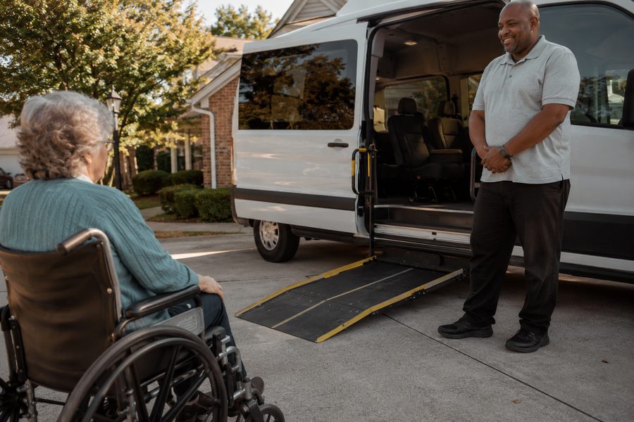 A driver stands by our wheelchair-accessible van with the ramp lowered, ready for a rider